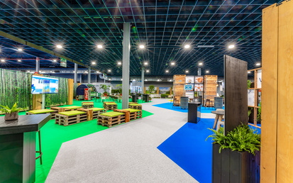 Exhibition booths at VIV Europe inside of big event hall around sustainable carpet path in grey, blue and green