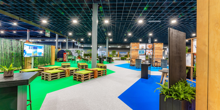 Exhibition booths at VIV Europe inside of big event hall around sustainable carpet path in grey, blue and green