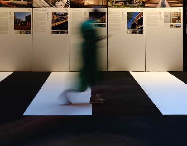 motion-blurred person walking on black and white striped carpet adjacent to exhibition walls