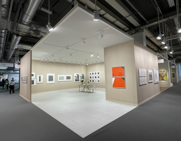 Art exhibition booth with beige walls and white ceiling, paintings hanging on the walls