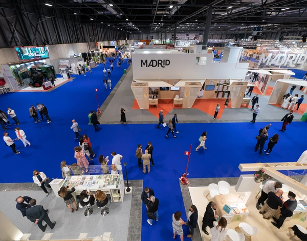 Top down view on people at exhibitions stands at event hall IFEMA Madrid with blue event carpet pathways between white booths